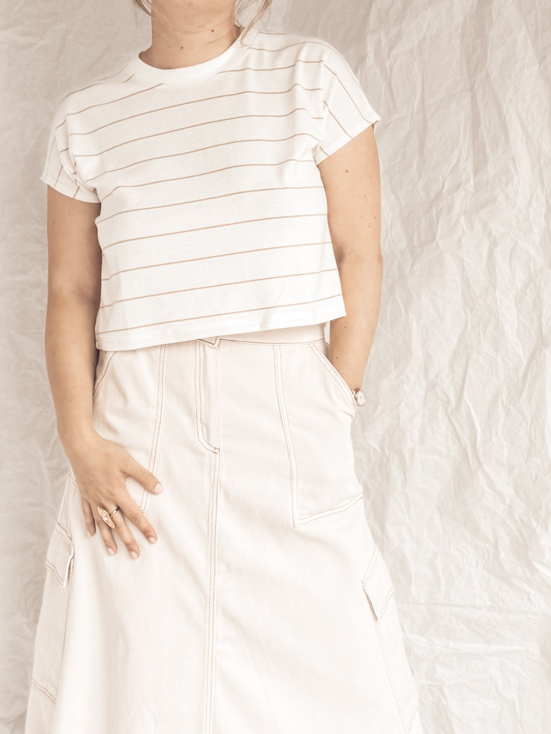 Person wearing a white striped shirt and white pants against a plain white background