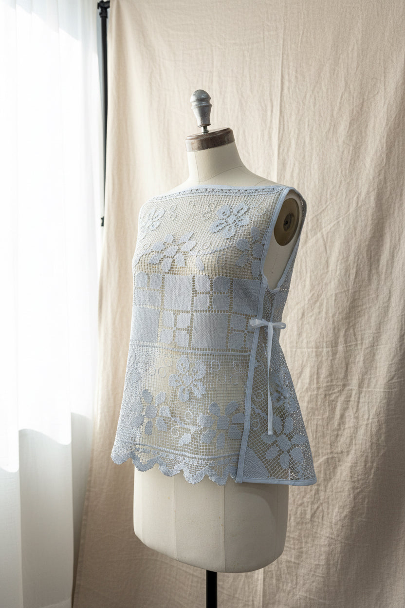 Light blue lace top on a mannequin against a neutral background